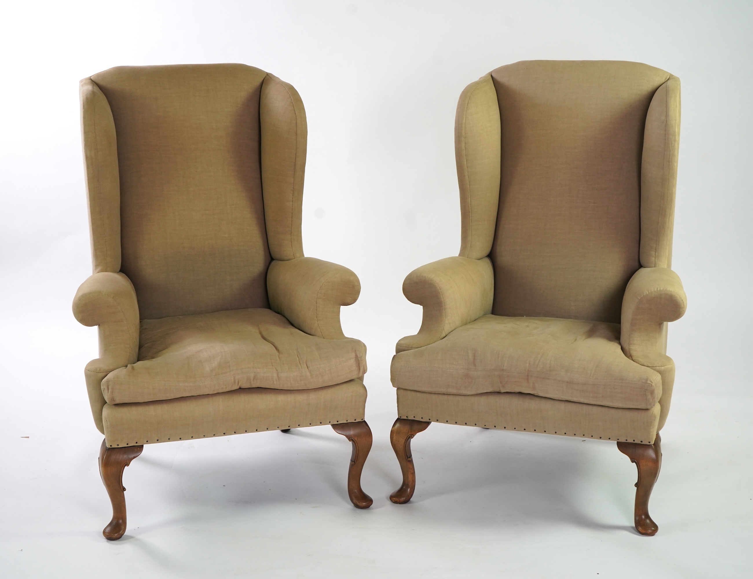 A pair of late 19th / early 20th century George II style upholstered wing armchairs